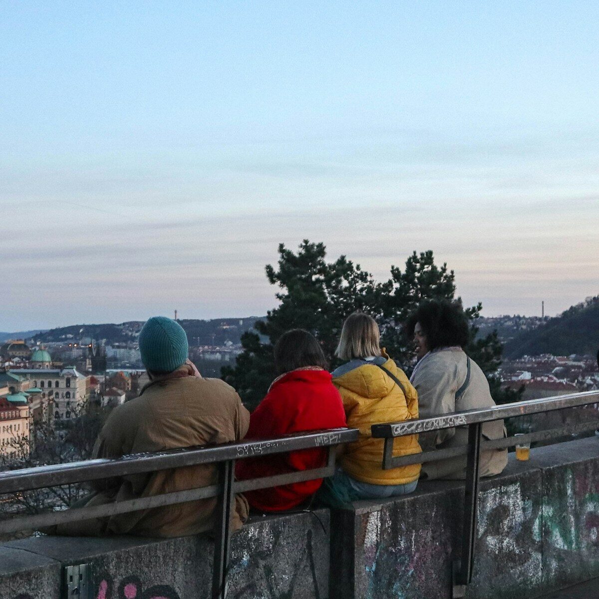 a group of people sitting on a railing overlooking a city