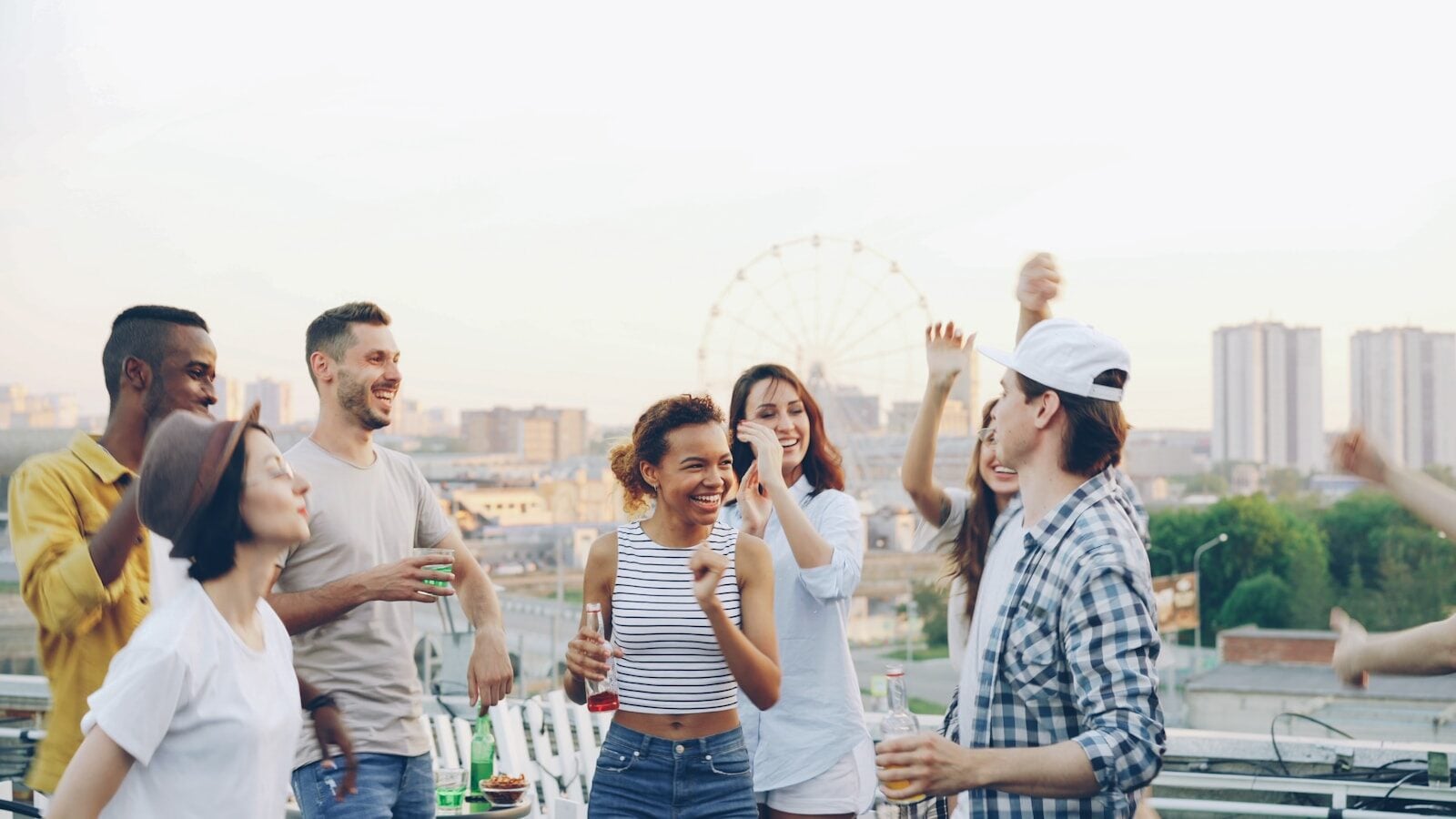 Group of friends dancing and celebrating on a rooftop.